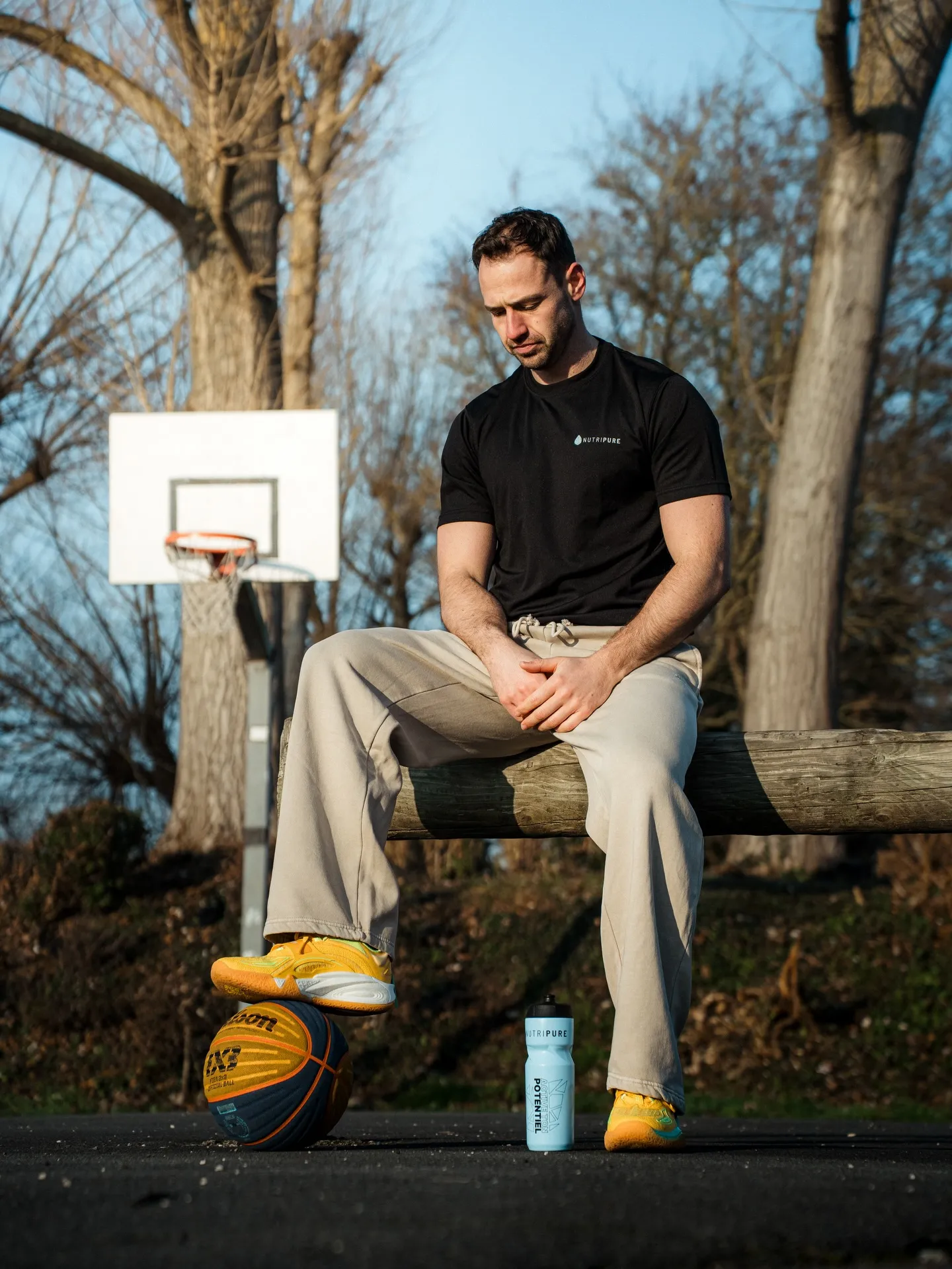 Paul assis sur un banc de playground, tenue Nutripure, ballon au pied et gourde posée au sol